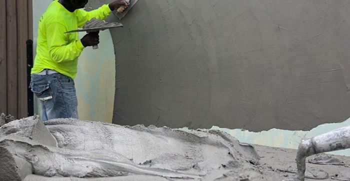 A man is plastering a wall with a trowel.
