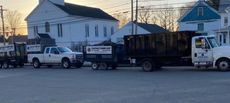 Several trucks parked on a street. A church and other buildings are in the background.
