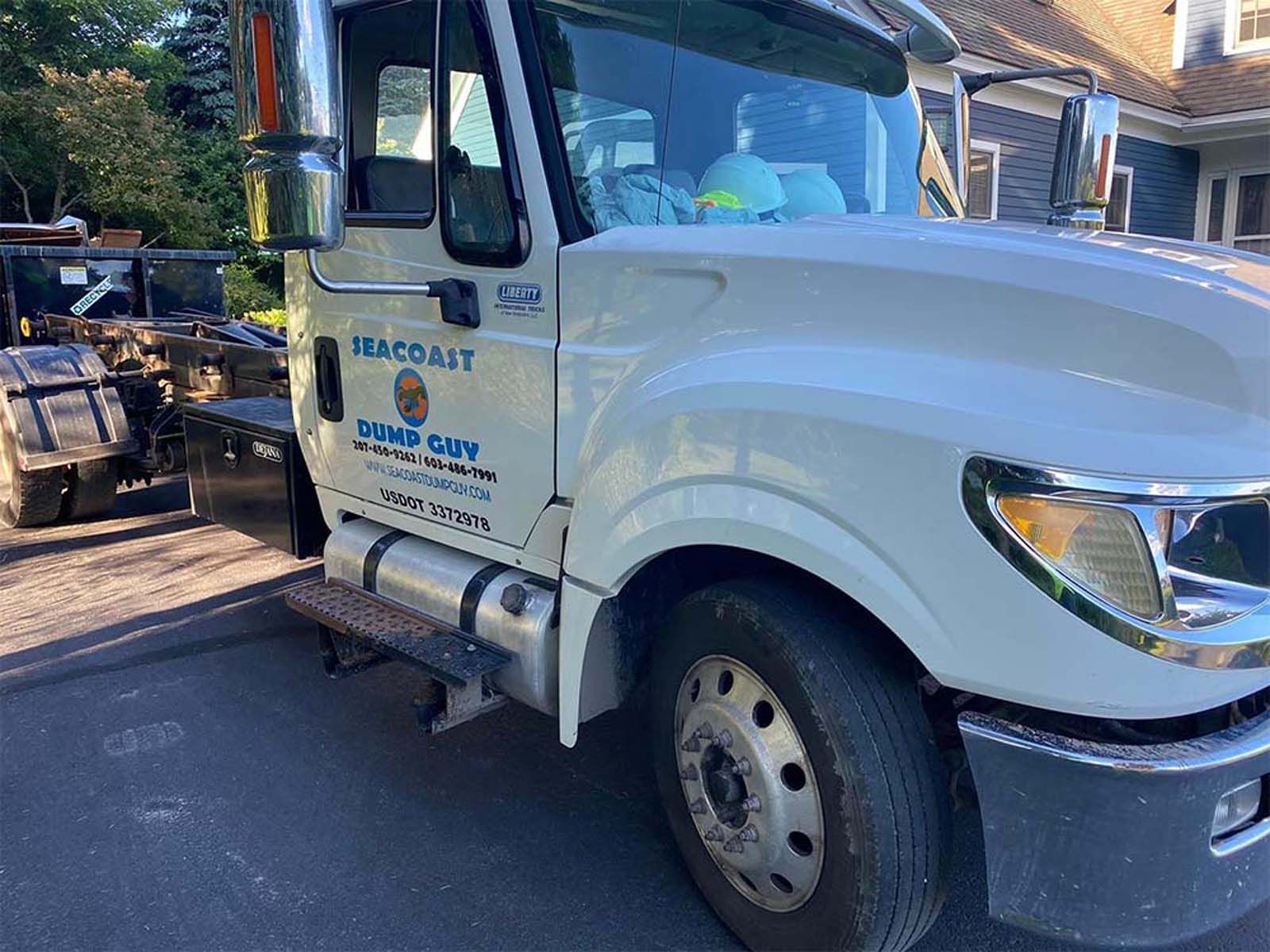 White dump truck parked on a paved driveway with 