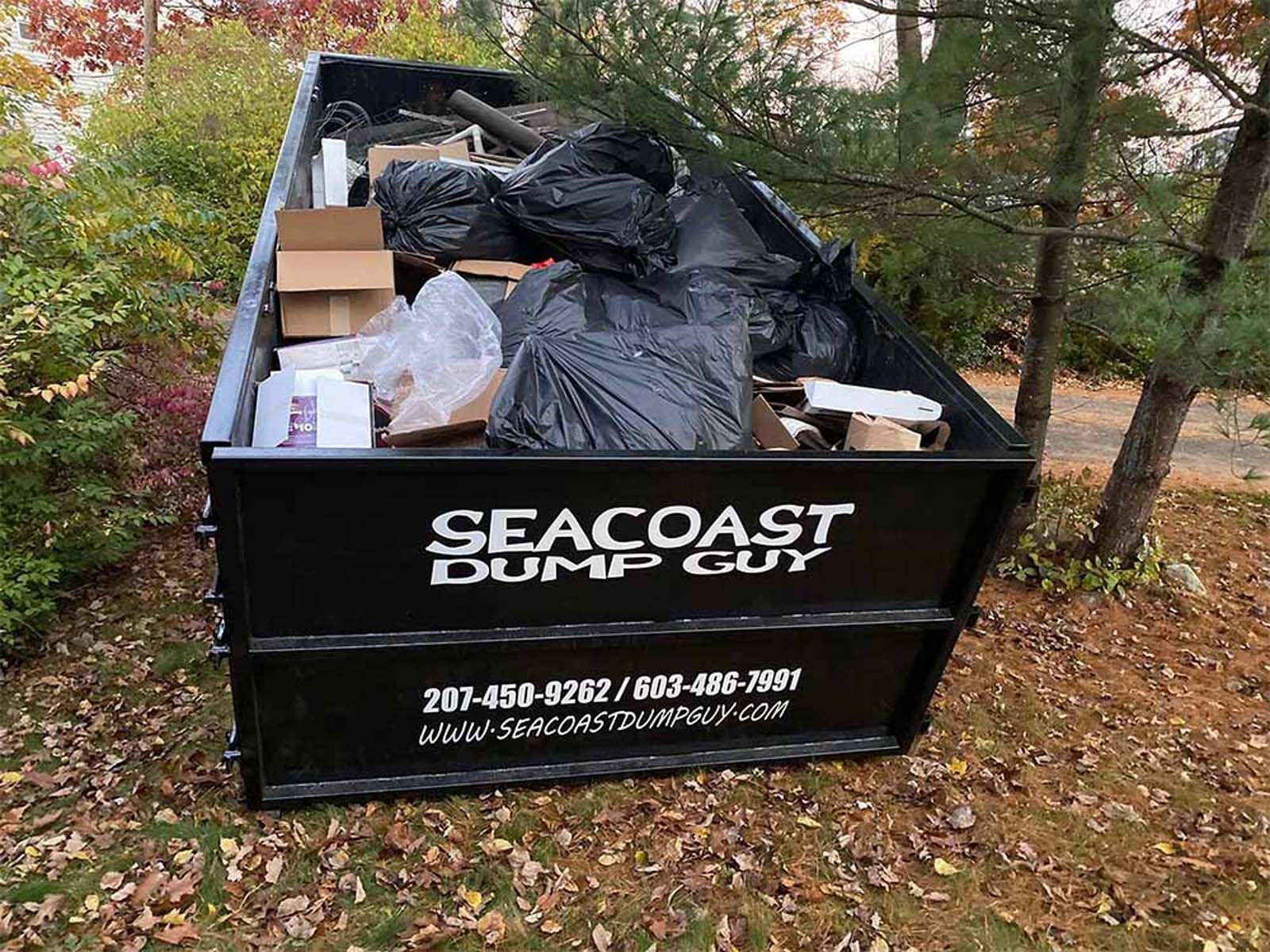 Black dumpster filled with trash, text 