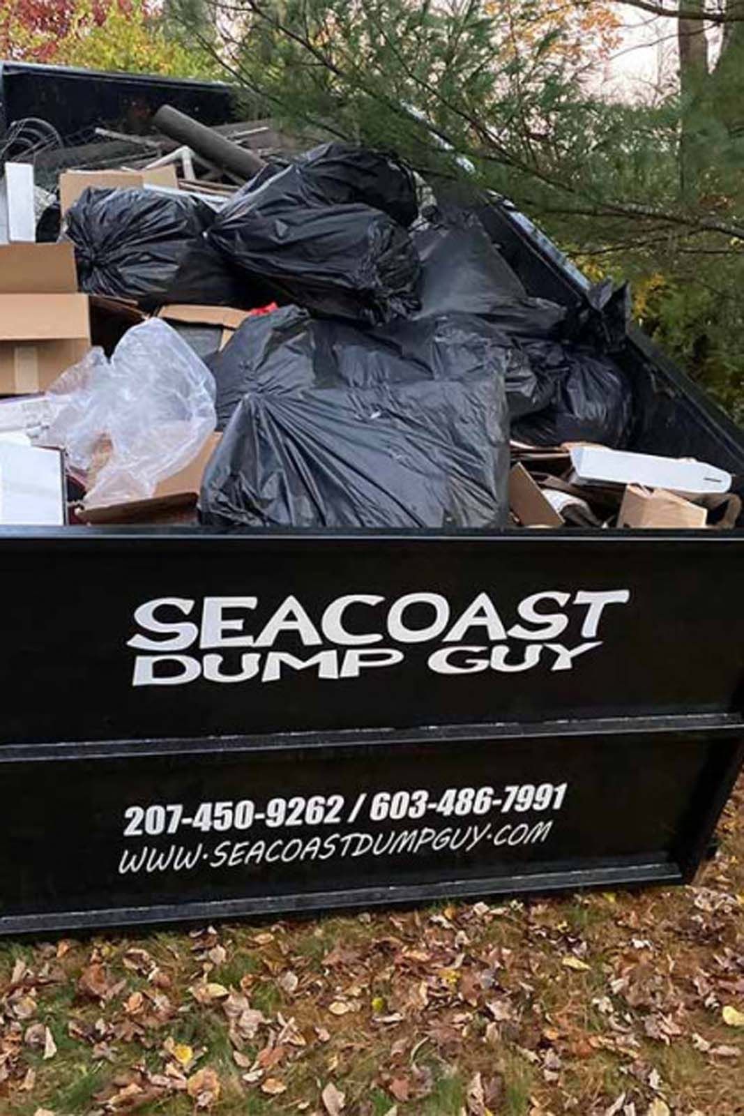 Black dumpster filled with trash, with 