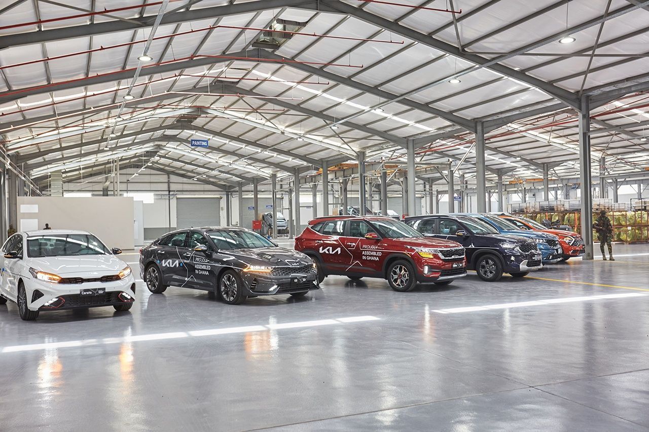 A row of cars are parked in a large warehouse.