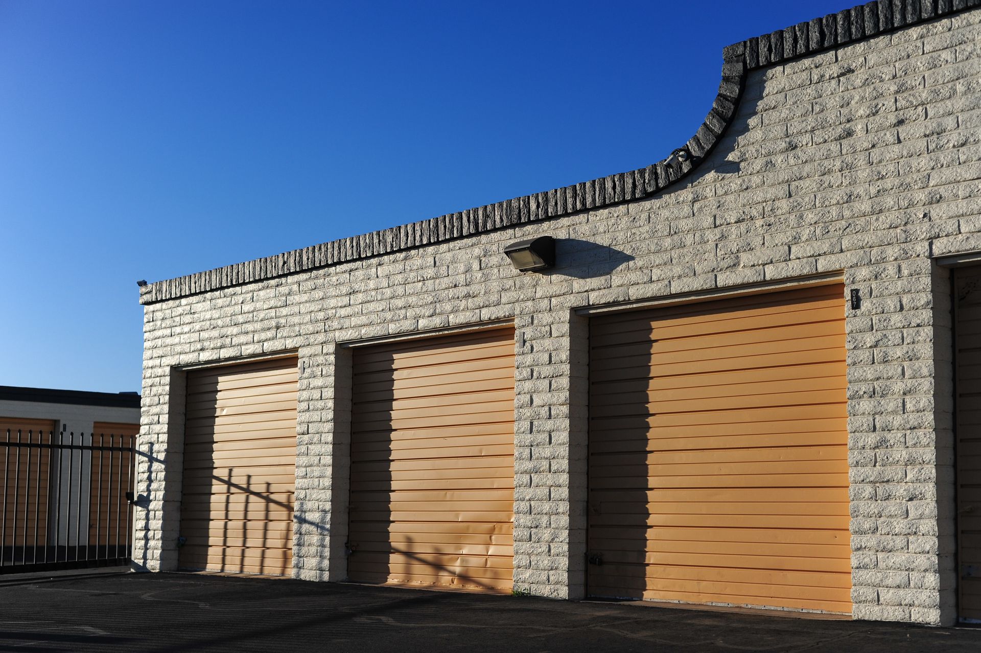 Exterior of a storage building with several closed roll up doors in bright daylight.