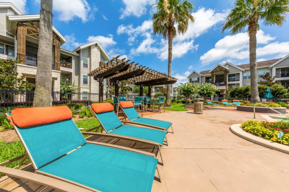 A row of lounge chairs are lined up in front of a swimming pool at Marquis at Sugar Land in Sugar Land, TX.