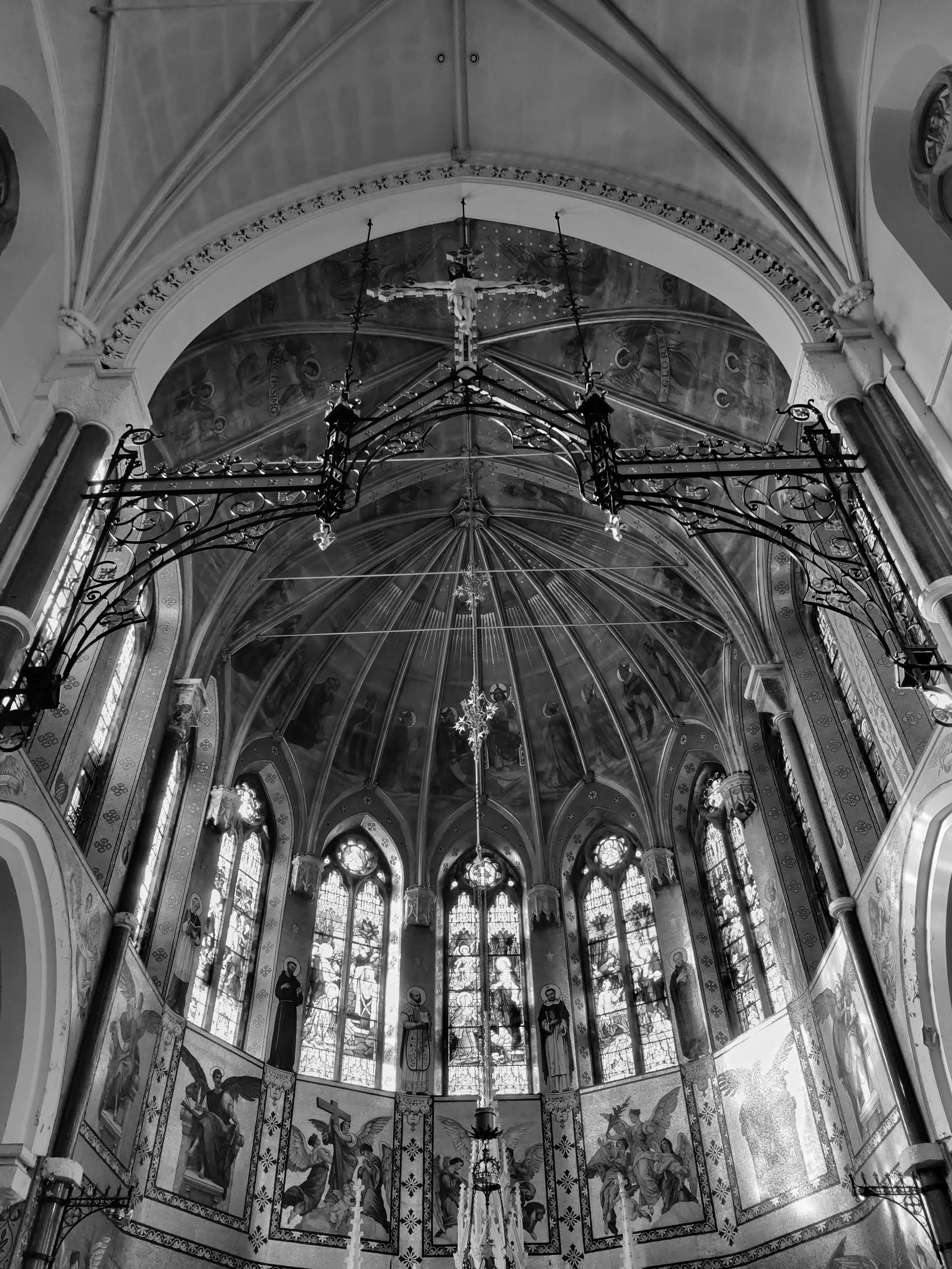 Interior of a church with arched ceiling, stained glass windows, and intricate artwork.