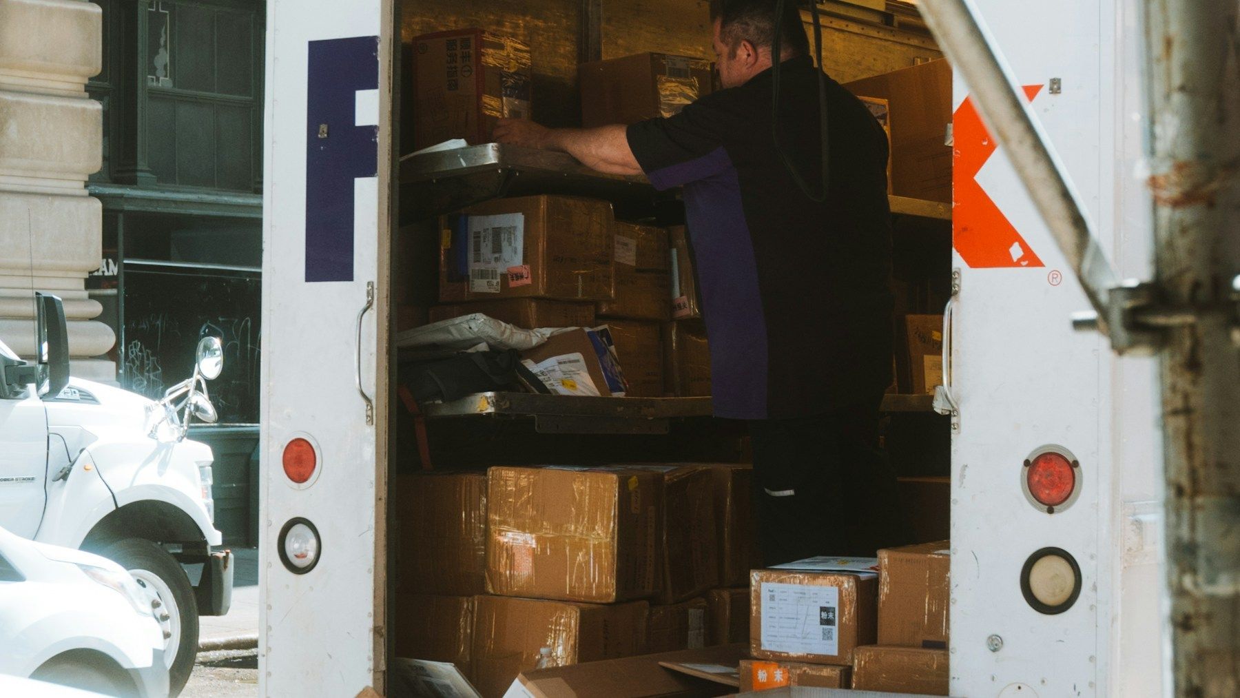 Courier loading cardboard parcels into a delivery vehicle for a same-day business service