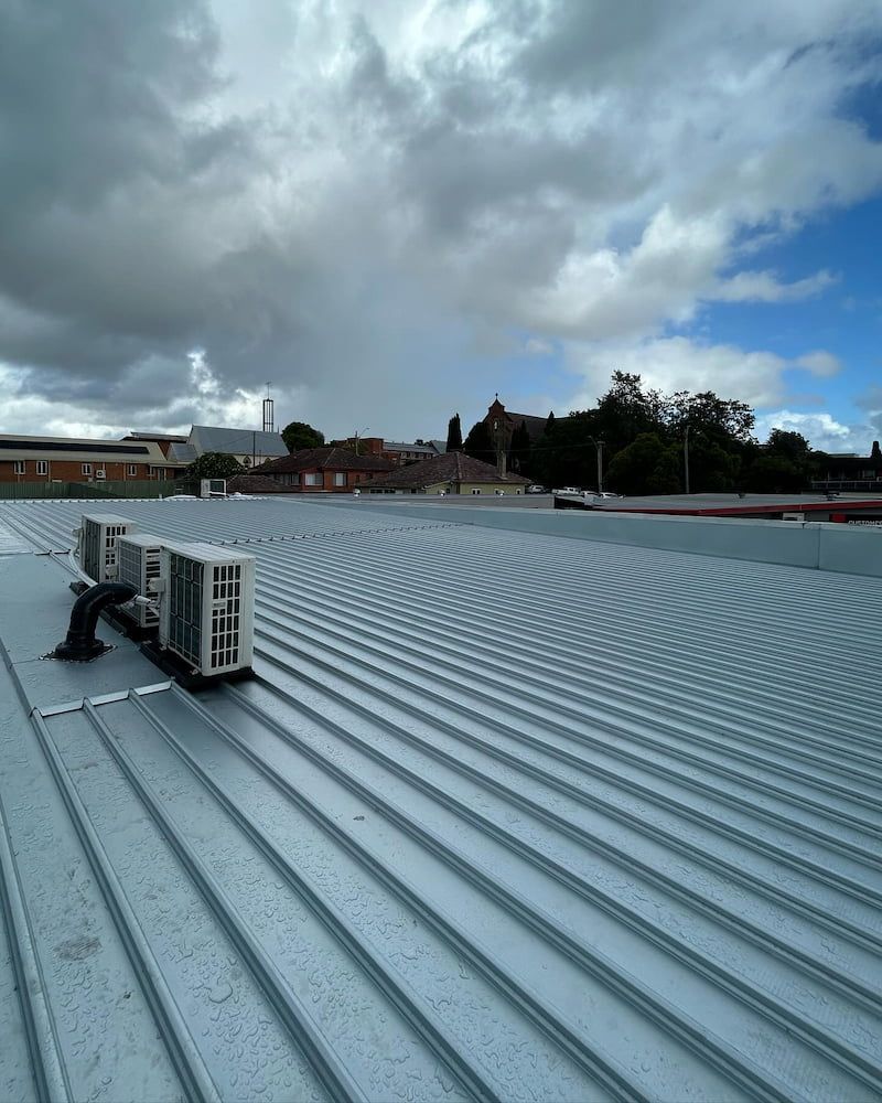 Metal Corrugated Roof With Air Conditioning Units, Overcast Sky in Background — Ace1 Metal Roofing in Nabiac, NSW