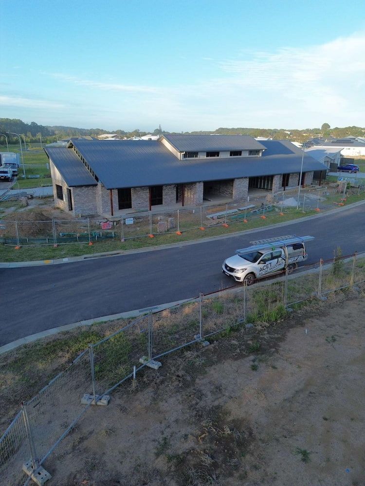 Long, Low House Under Construction, Grey Roof, White Vehicle Driving on a Road — Ace1 Metal Roofing in Wingham, NSW