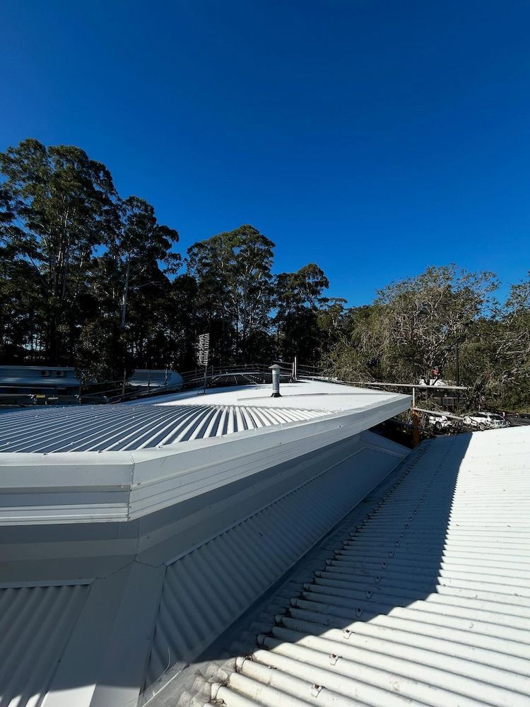 White Corrugated Roof With Chimneys, Trees Against a Blue Sky — Ace1 Metal Roofing in Laurieton, NSW