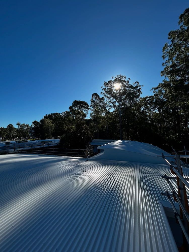 Long Shadows Cast on a Corrugated Metal Roof Under a Clear Blue Sky — Ace1 Metal Roofing in Laurieton, NSW