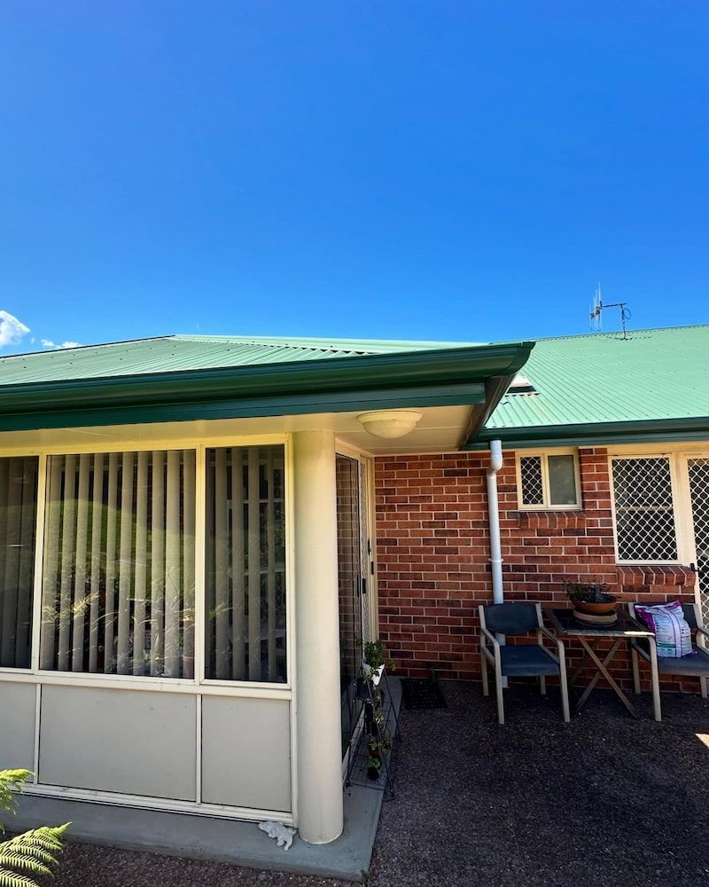 Brick Building Exterior With Green Roof and Blue Sky — Ace1 Metal Roofing in Taree, NSW
