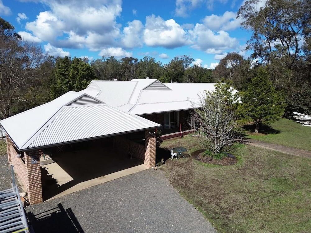 An Aerial View of a House With a White Roof and a Carport  — Ace1 Metal Roofing in Taree, NSW
