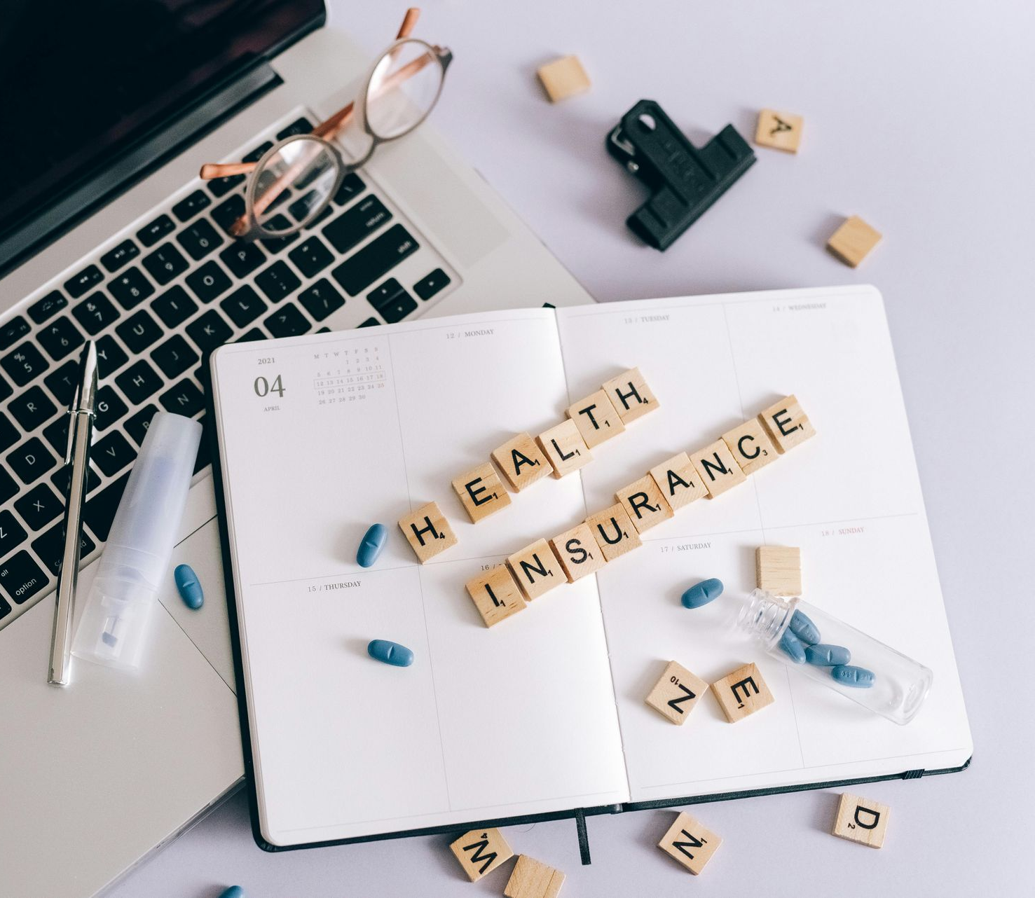 Laptop, open notebook, and scattered pills with wooden letters spelling 