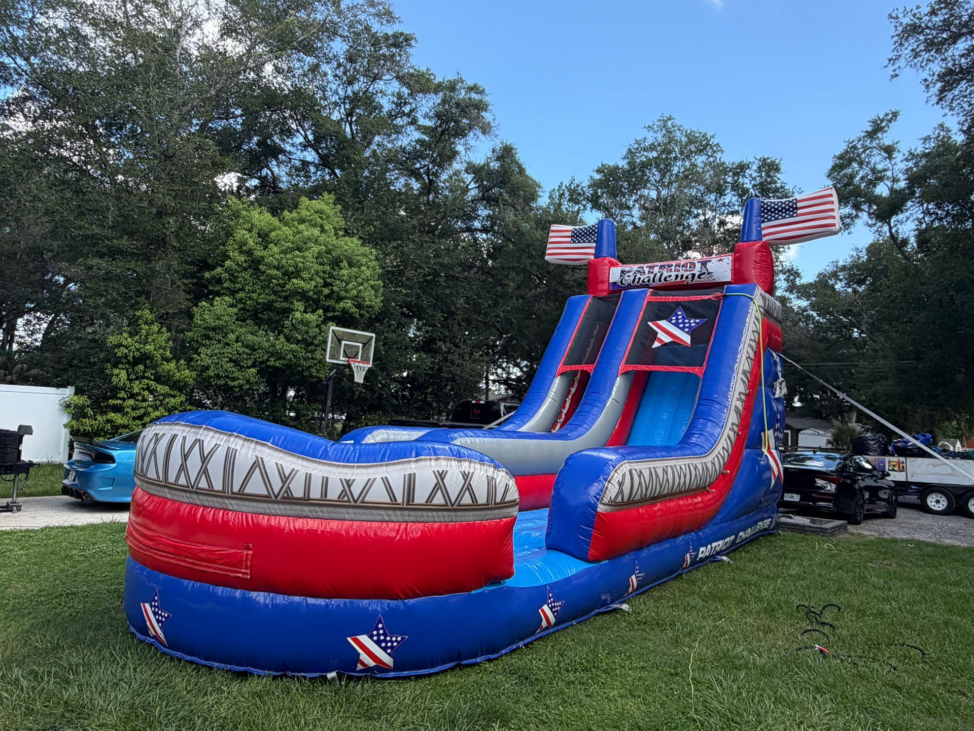 Red, white, and blue inflatable water slide with U.S. flags on a grassy lawn outdoors