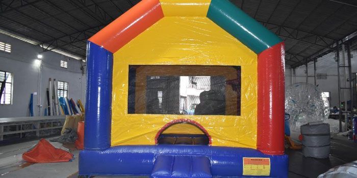 A colorful, inflatable bounce house stands in a large indoor warehouse.