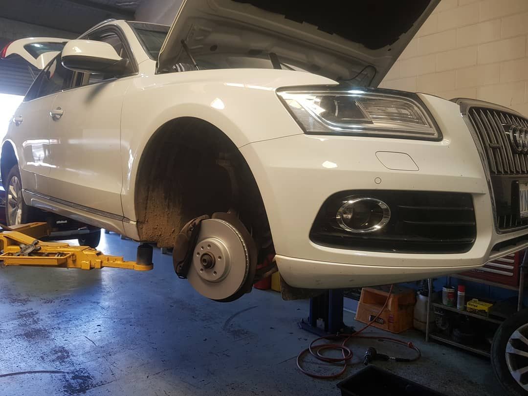 A White Car with The Hood Open Is on A Lift in A Garage — Latin Motors in Queanbeyan, ACT