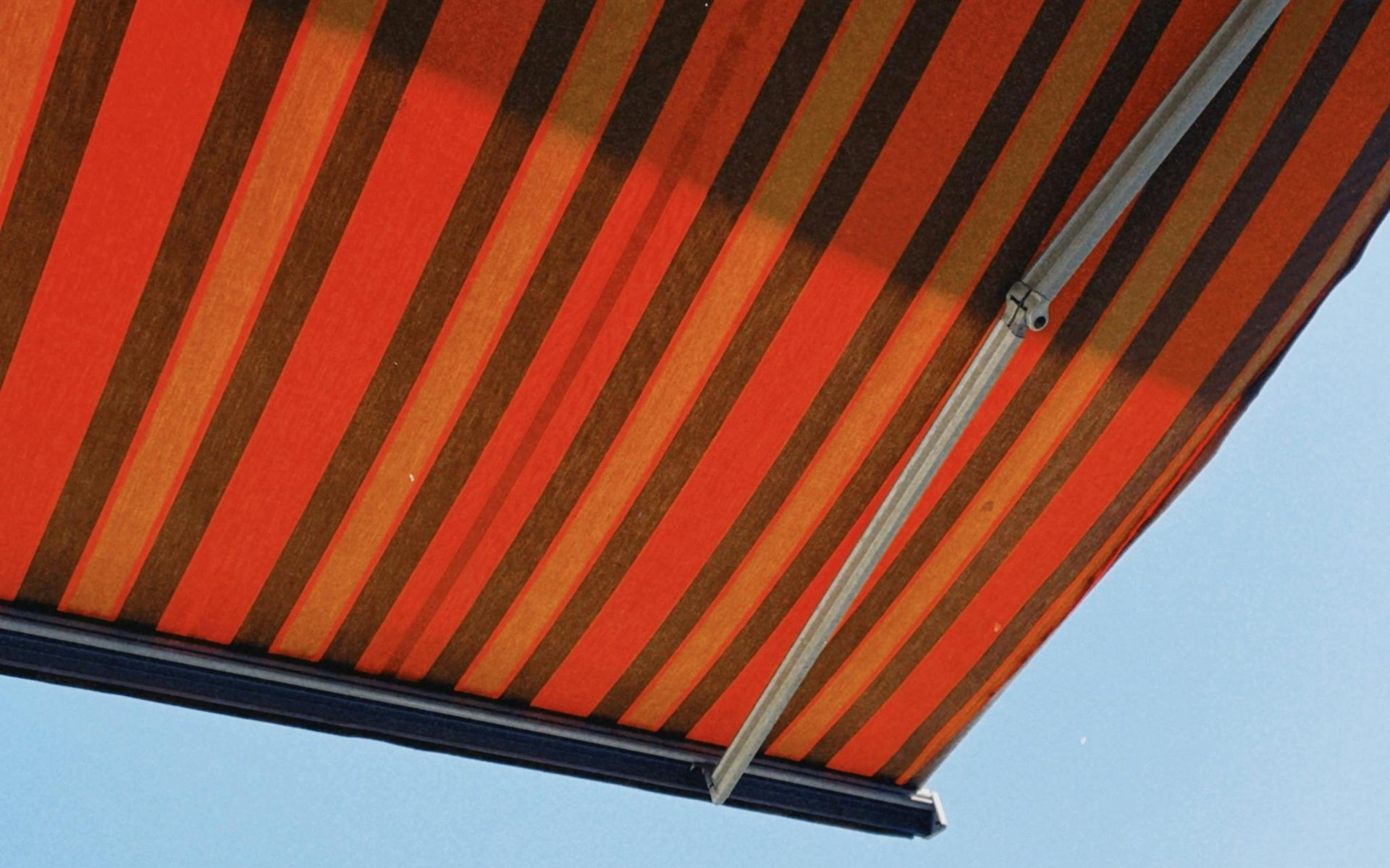 Striped orange and brown retractable awning for patio shade.