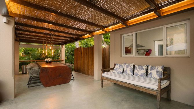 Rustic bamboo patio roof over a wooden outdoor sofa set.