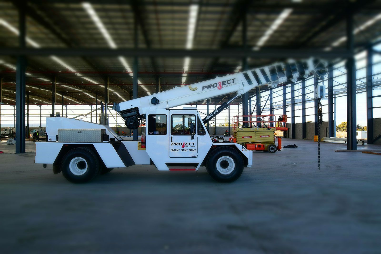A white crane is parked in a large warehouse.