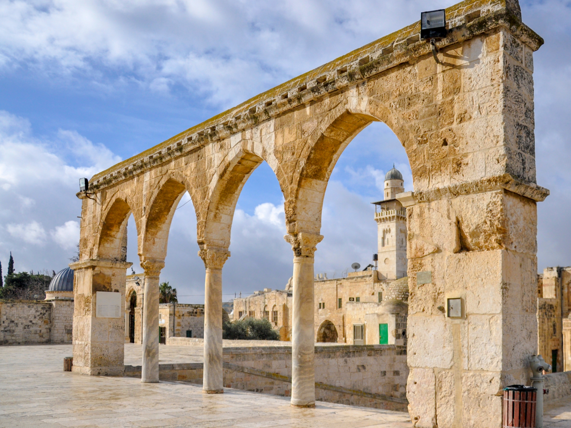 A stone archway with columns and arches in front of a mosque.