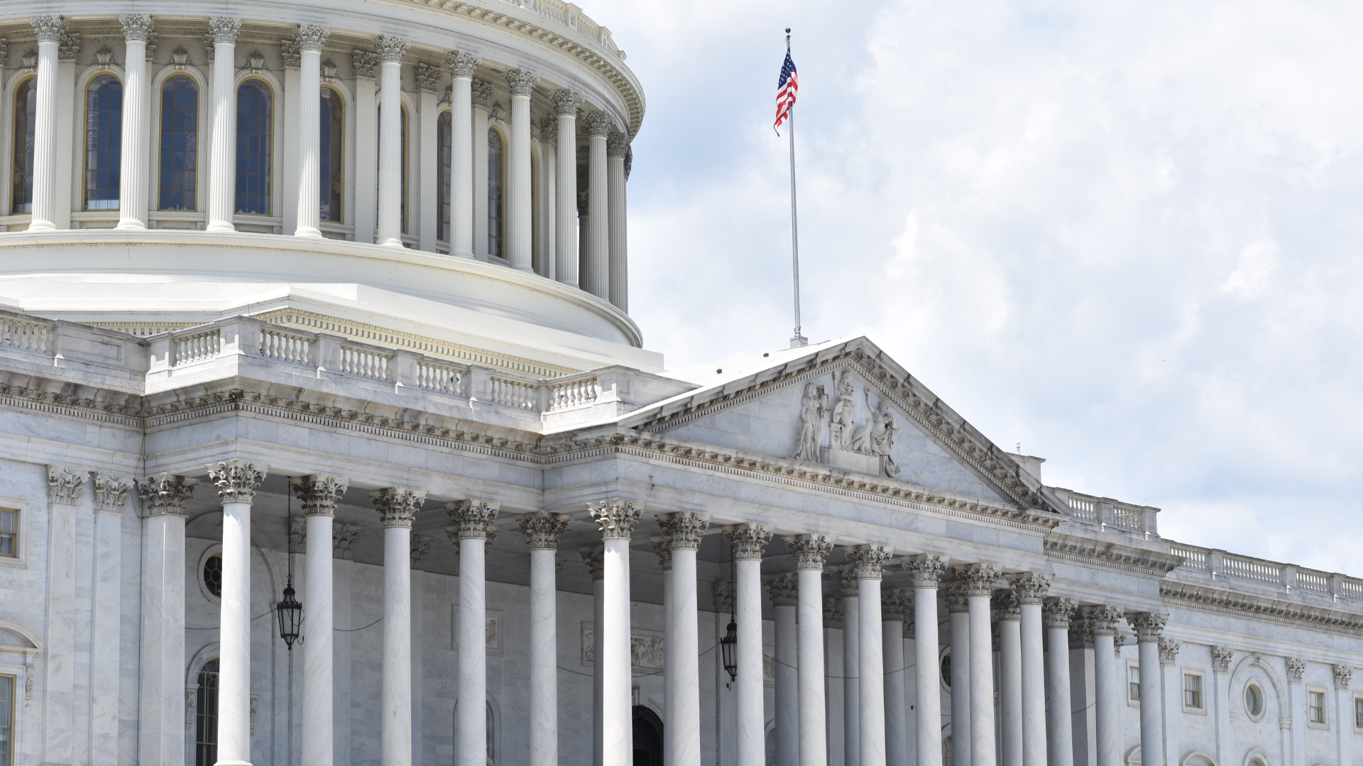 A large white building with columns and a flag on top of it.