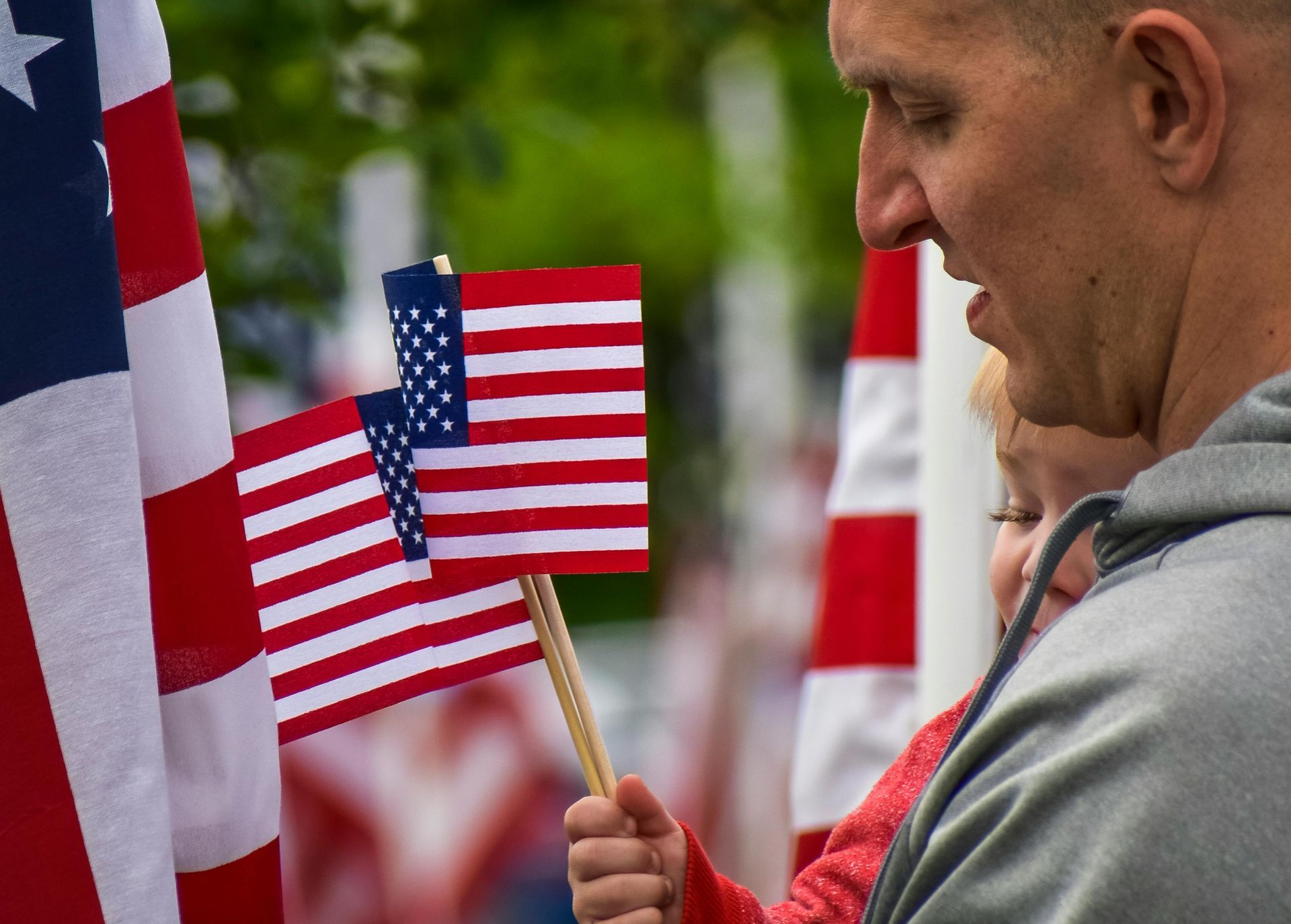 Man and child hold American flags among many others.