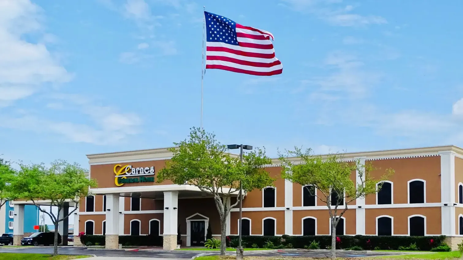 A brown two-story hotel with a large American flag waving in the wind.