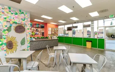 Brightly lit cafe with seating, counter, and sunflower mural.