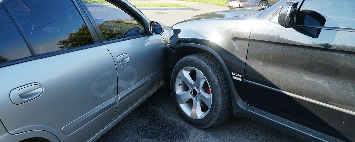 Two cars, silver sedan and black SUV, sideswiped and damaged.