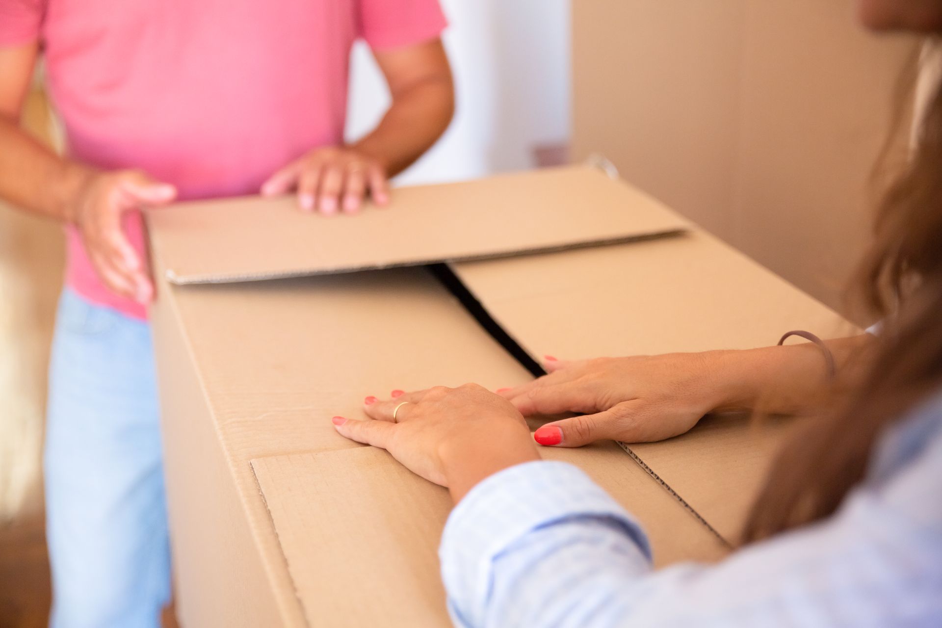 Personas levantando una caja de cartón de mudanza.