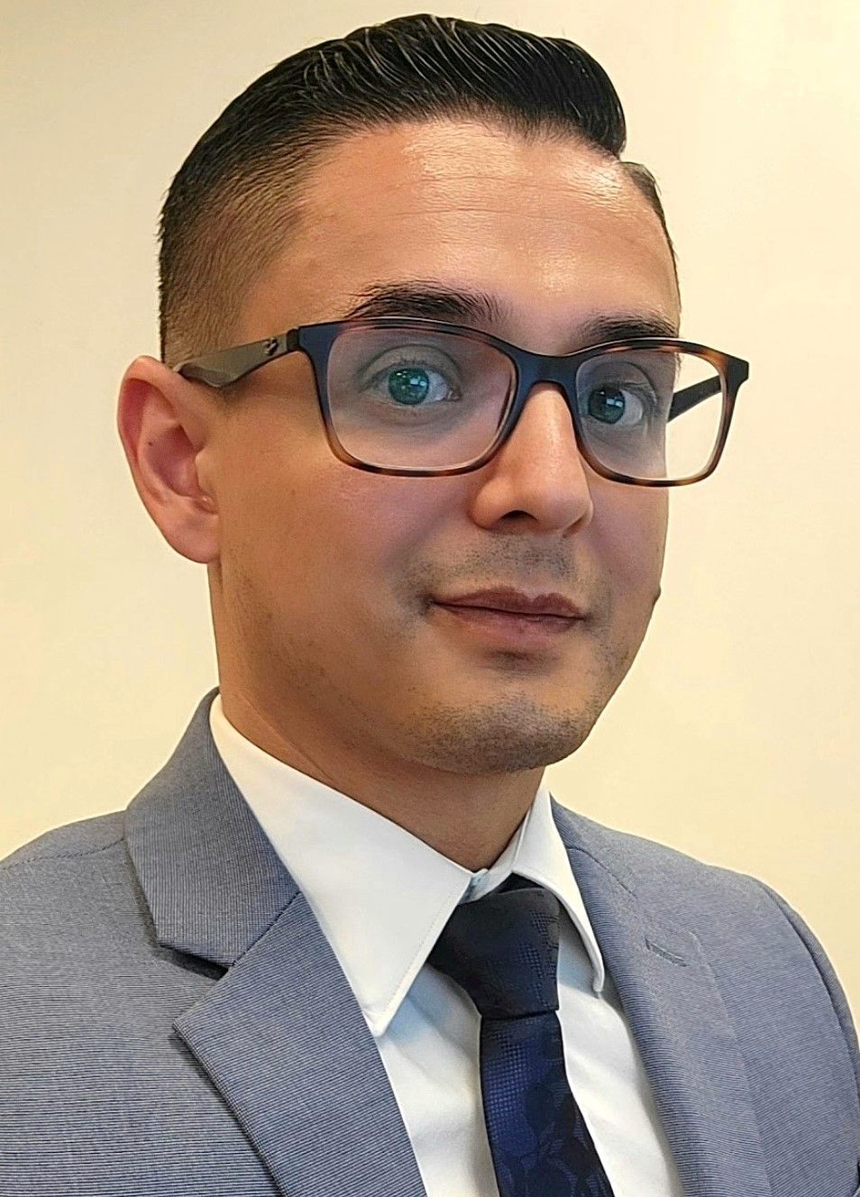 JP Rueda Man wearing glasses and suit, looking towards the camera.