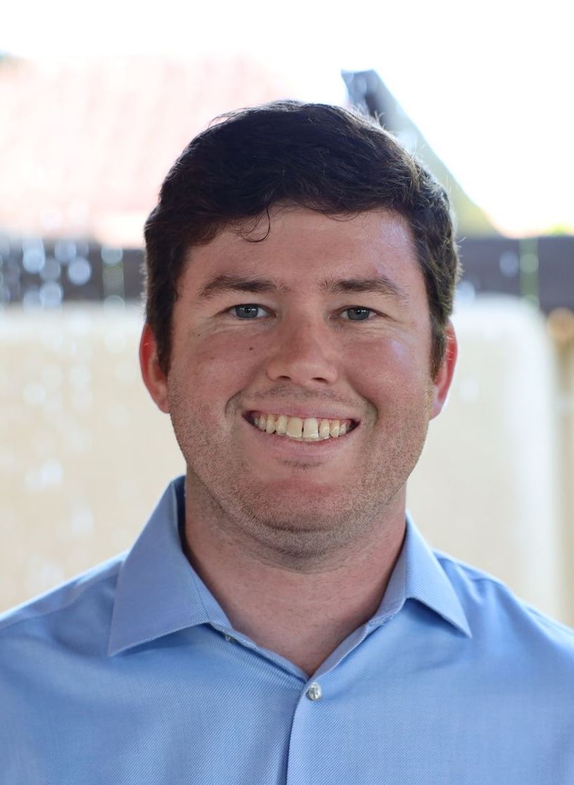 A man in a blue shirt is smiling for the camera