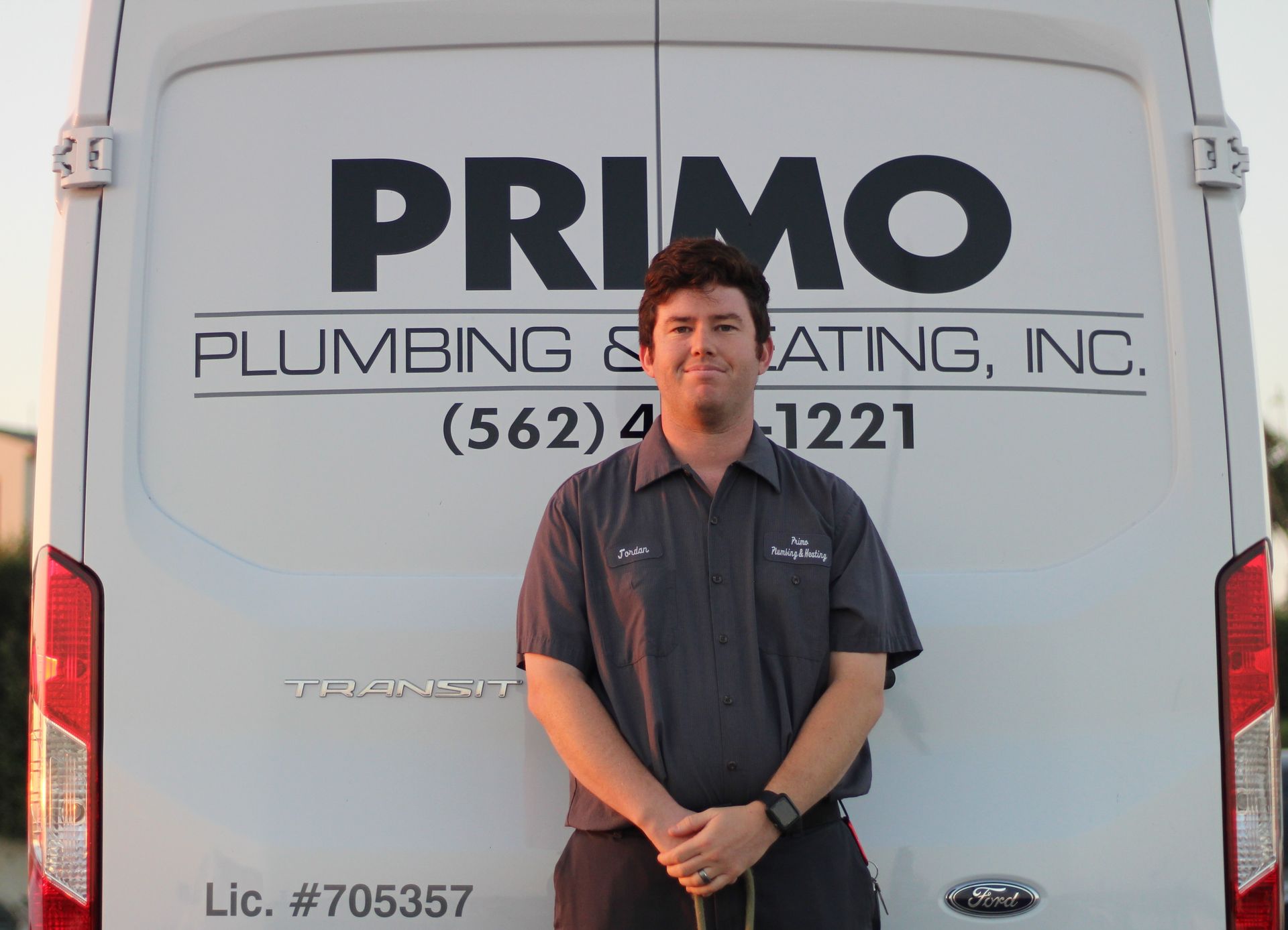 A man is standing in front of a primo plumbing and heating van