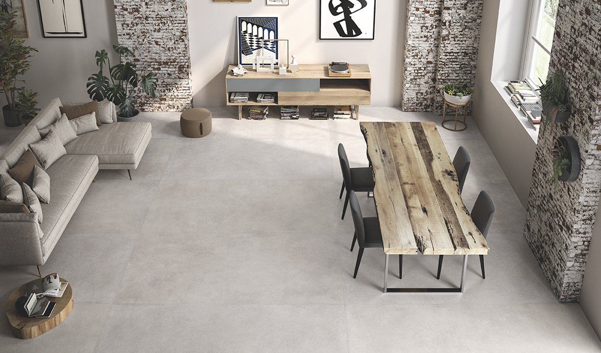 Luminoso soggiorno moderno con divano chiaro, lungo tavolo in legno e pareti con inserti in pietra.