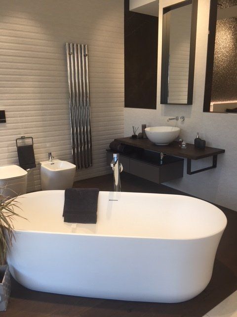 Bagno moderno con vasca freestanding bianca, mobile lavabo doppio e specchio a parete con illuminazione calda.