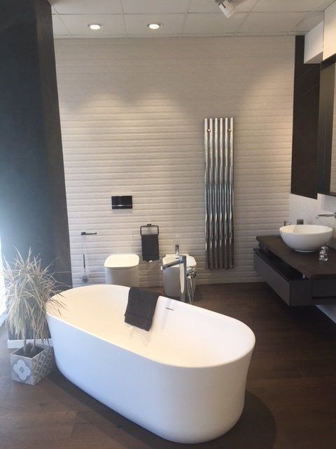 Bagno moderno con vasca freestanding bianca, lavabo a ciotola, dettagli in legno scuro e scaldasalviette cromato.