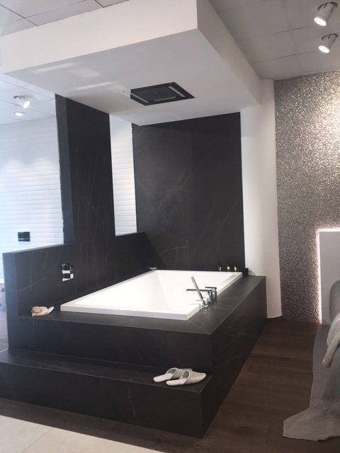 Bagno moderno con vasca da bagno, rubinetteria per la doccia e pannelli a parete con finitura materica in bianco e nero.