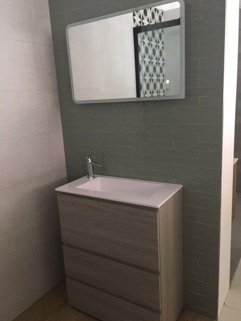 Mobile bagno moderno con lavabo, specchio e parete decorativa rivestita con piastrelle verdi.