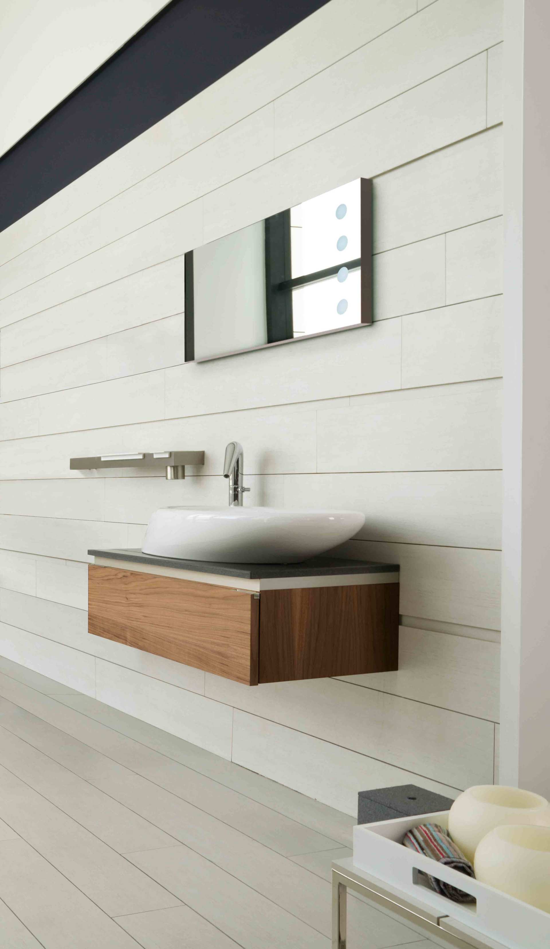 Mobile bagno moderno con mobiletto sospeso in legno, lavabo bianco, specchio e rubinetto a parete su pannello a doghe bianche.