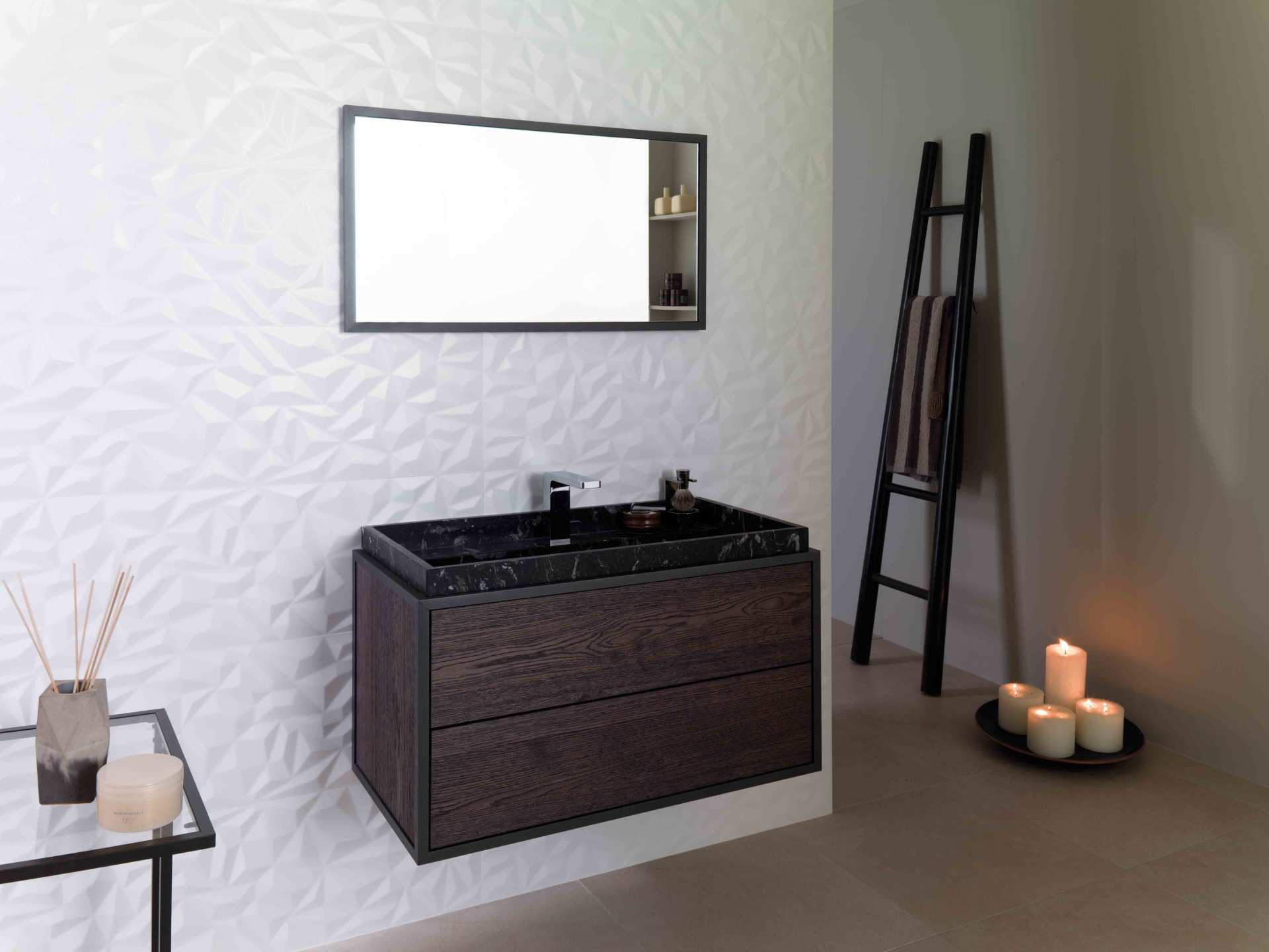 Bagno moderno con mobile lavabo scuro, specchio a parete, mensola a scala e candele sul pavimento.