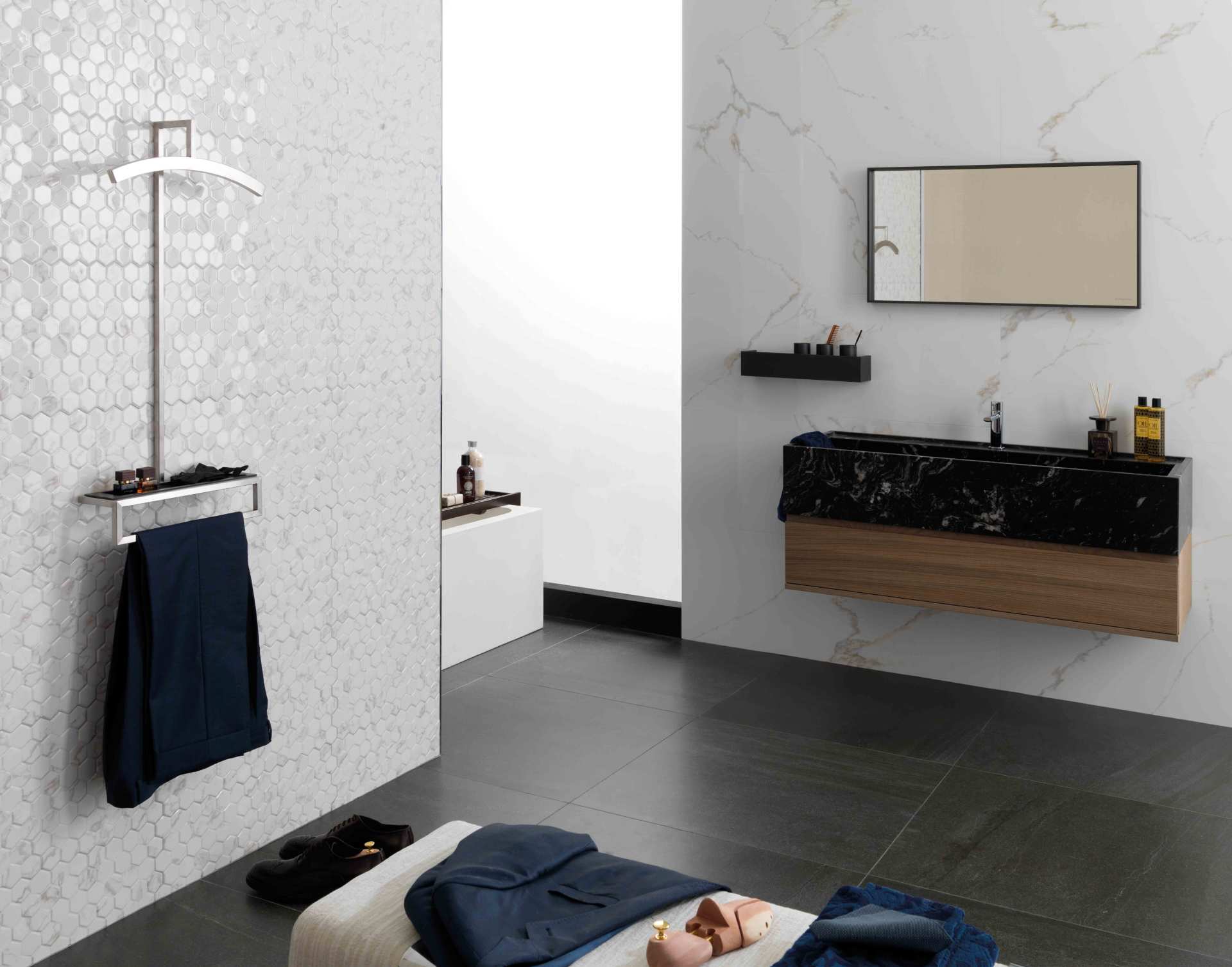 Bagno moderno con parete decorata, mobiletto nero, specchio, asciugamano e una persona sdraiata sul pavimento.