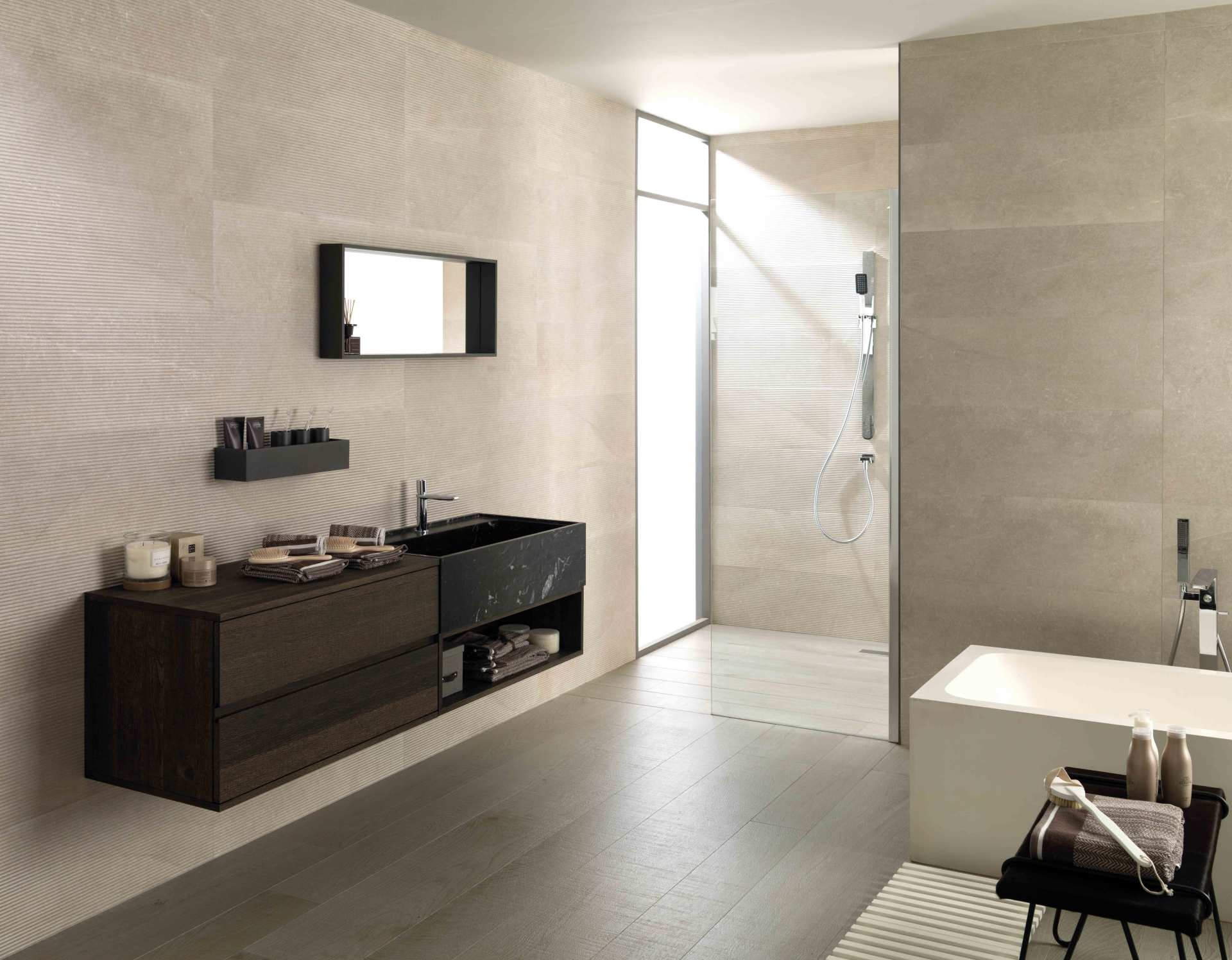 Bagno moderno e minimalista con mobile lavabo scuro, specchio a parete e cabina doccia nei toni del beige.