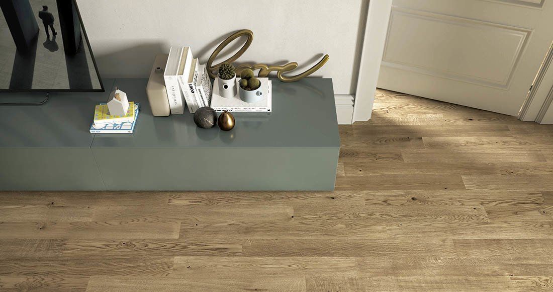 Un tavolino consolle grigio con una scatola di fazzoletti, oggetti decorativi e una tazza su un pavimento di legno in un'area di ingresso.