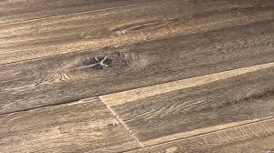 Primo piano di un pavimento in legno marrone consumato dagli agenti atmosferici, con venature e nodi ben visibili.