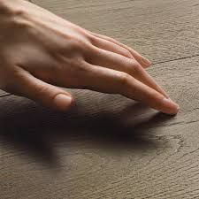 Una mano sfiora leggermente un piano di tavolo in legno dalla superficie ruvida.