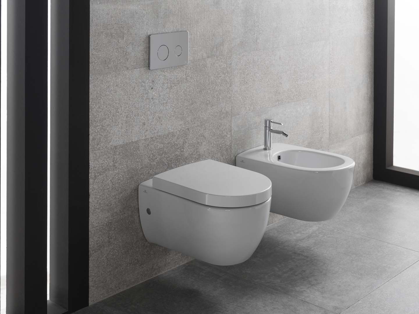 Bagno moderno con WC sospeso e bidet nei toni del grigio.