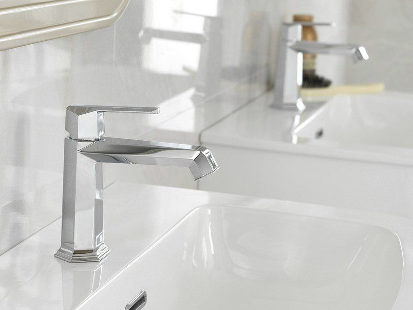Lavabo da bagno moderno di colore bianco con rubinetteria cromata e decorazioni minimaliste e luminose.