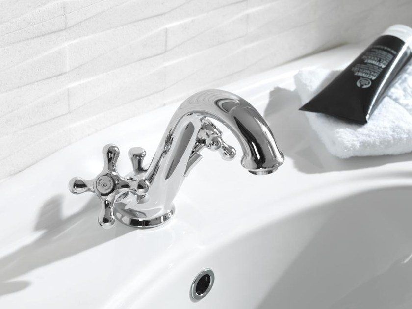 Rubinetto cromato sopra lavabo bianco con dispenser di sapone nero su asciugamano bianco