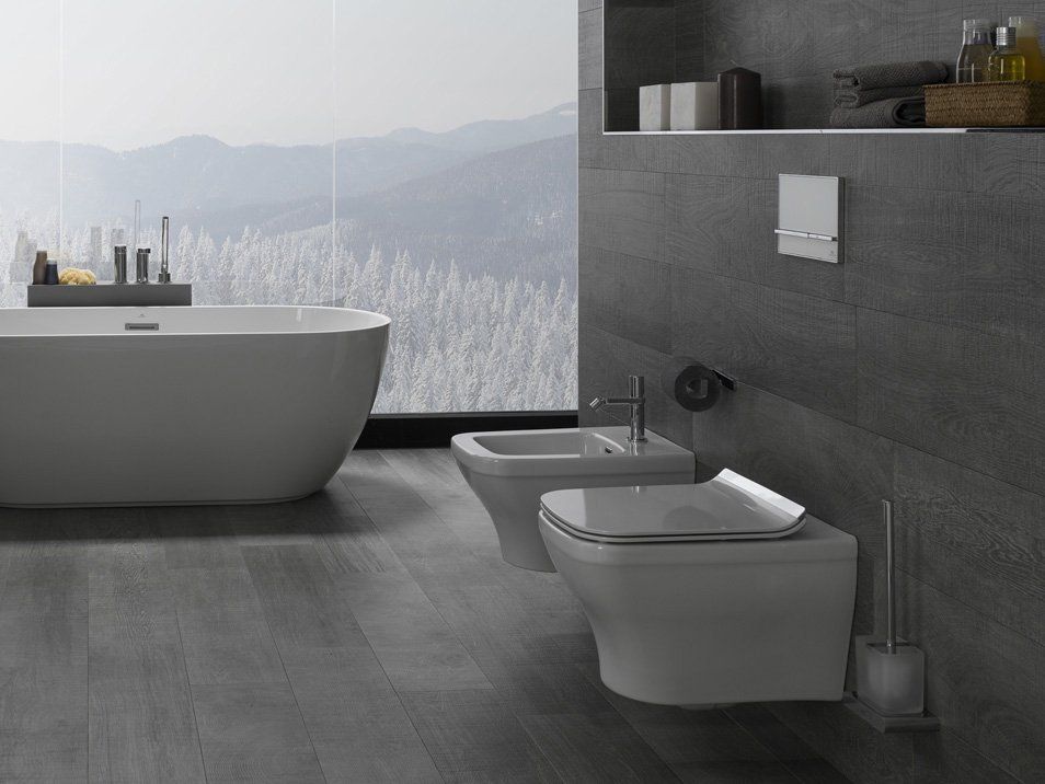 Bagno moderno di colore grigio con vasca freestanding, WC sospeso, bidet e finestra con vista sulle montagne.