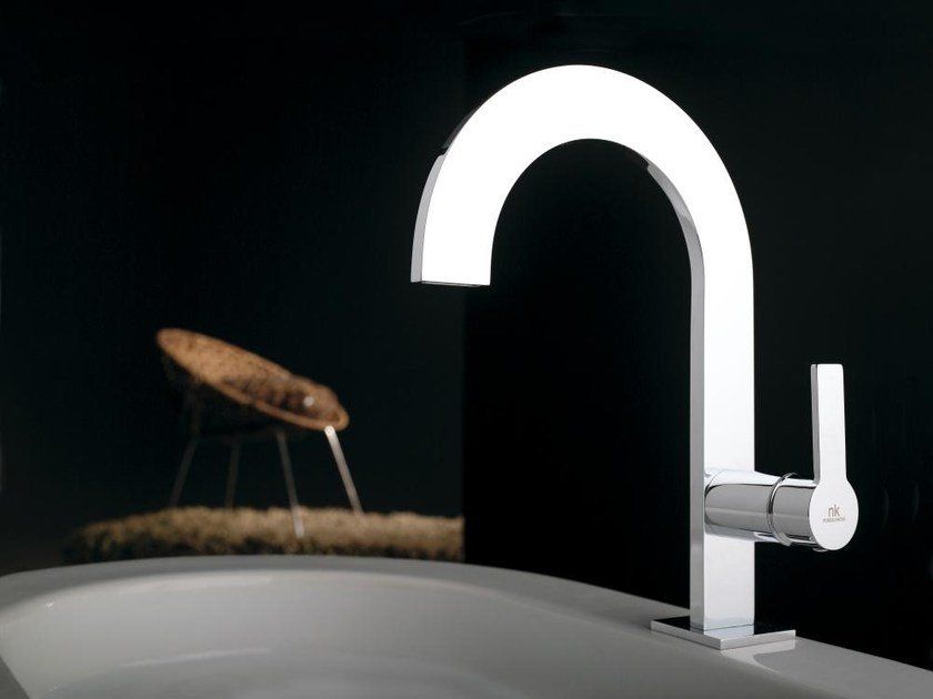 Rubinetto da cucina moderno di colore bianco con un insetto nero appollaiato su una spugna su sfondo scuro.